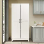 A freestanding white storage cabinet with two doors, positioned in a kitchen setting.