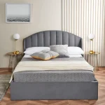 Modern grey upholstered bed with decorative pillows and side tables.